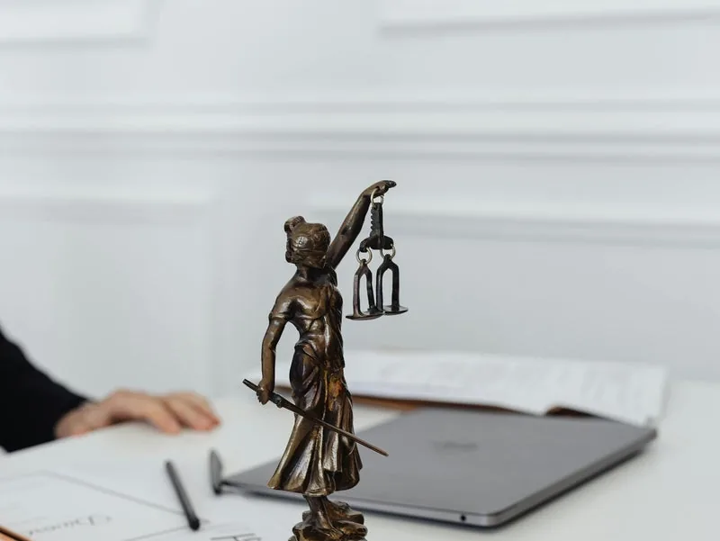 Statue of Lady Justice on a desk beside a laptop
